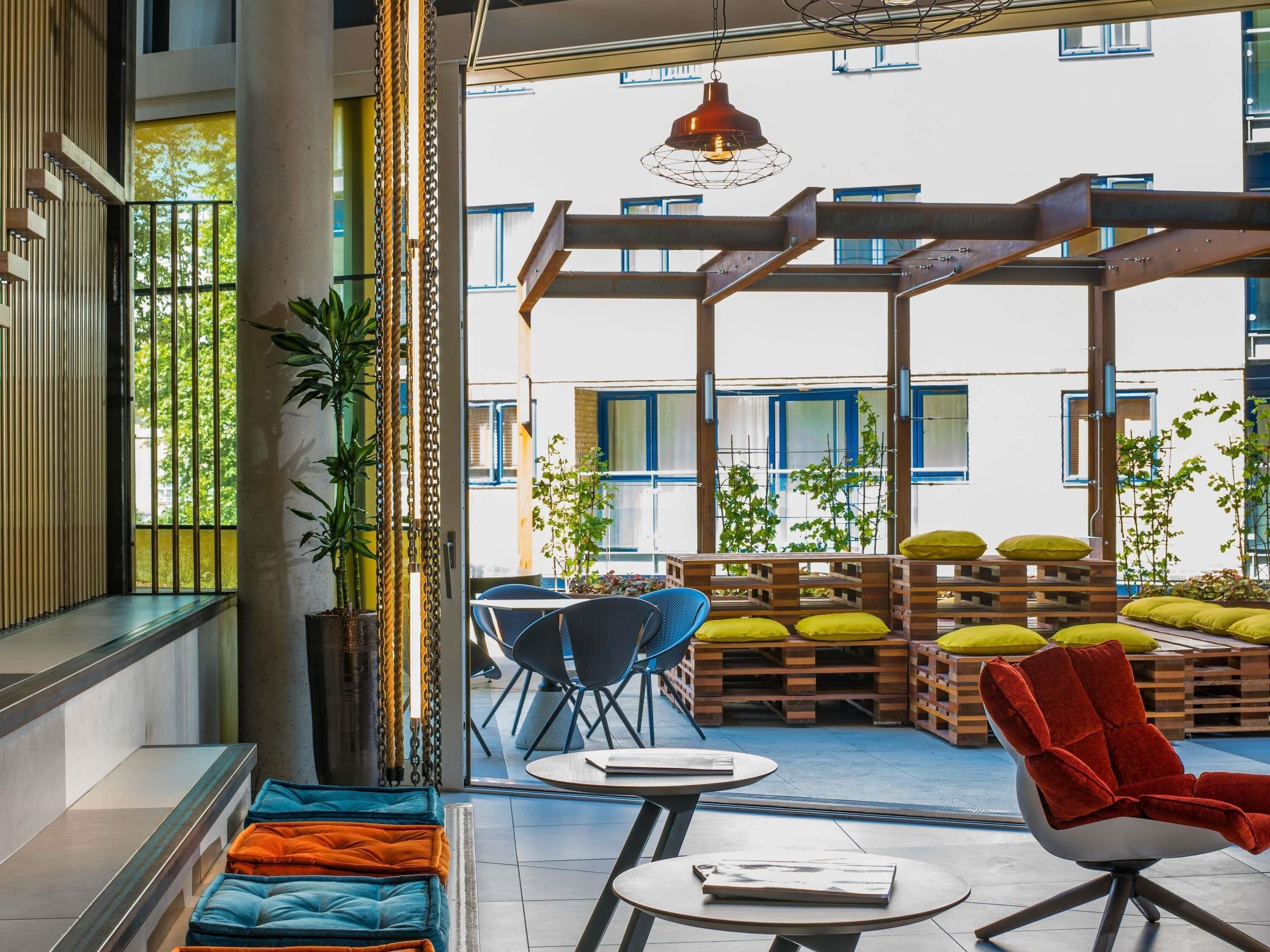 An indoor seating area with tables and chairs, a red chair, and wooden pallets with cushions.