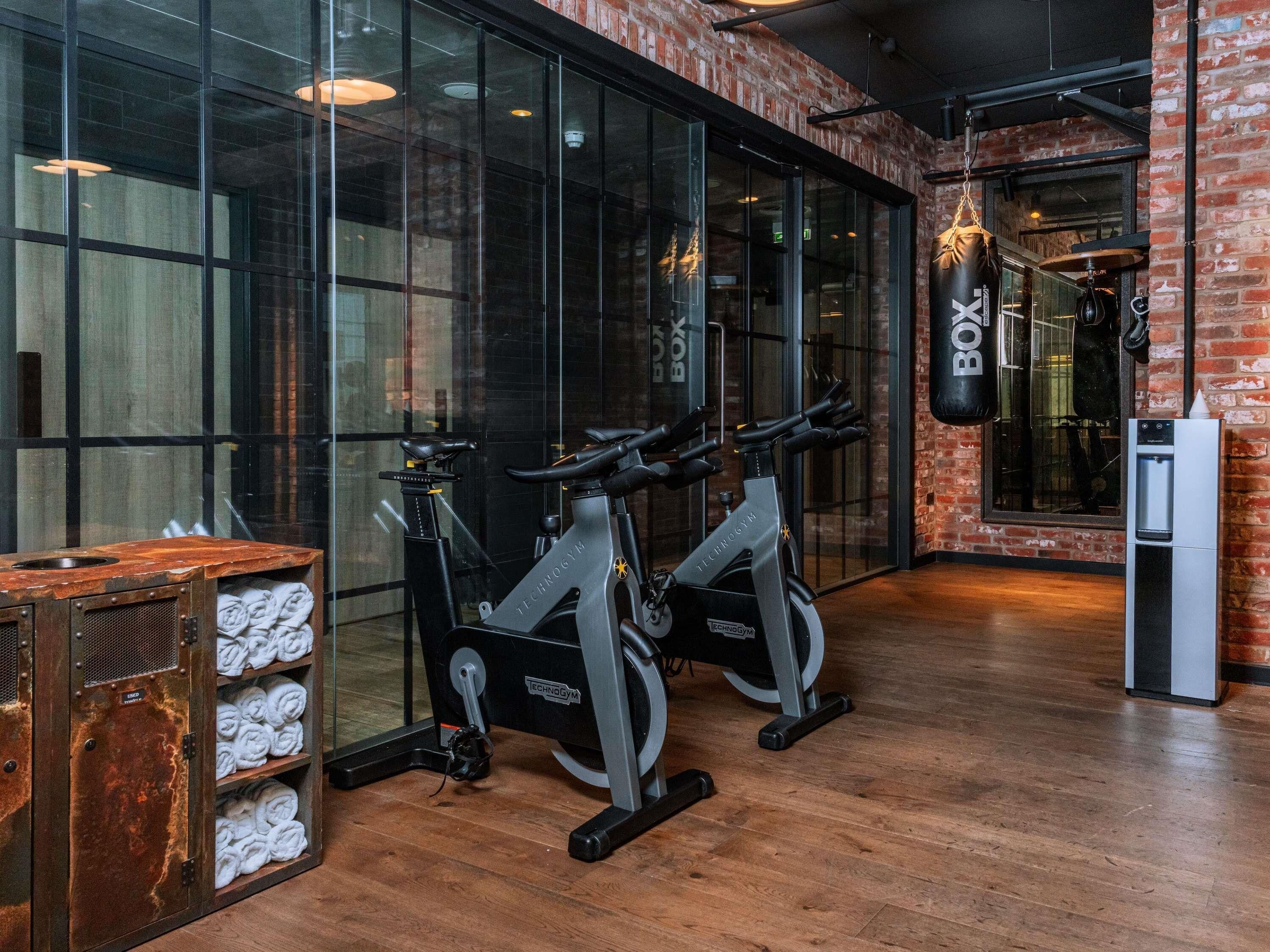 A gym with two stationary bikes, a punching bag, and a water dispenser.