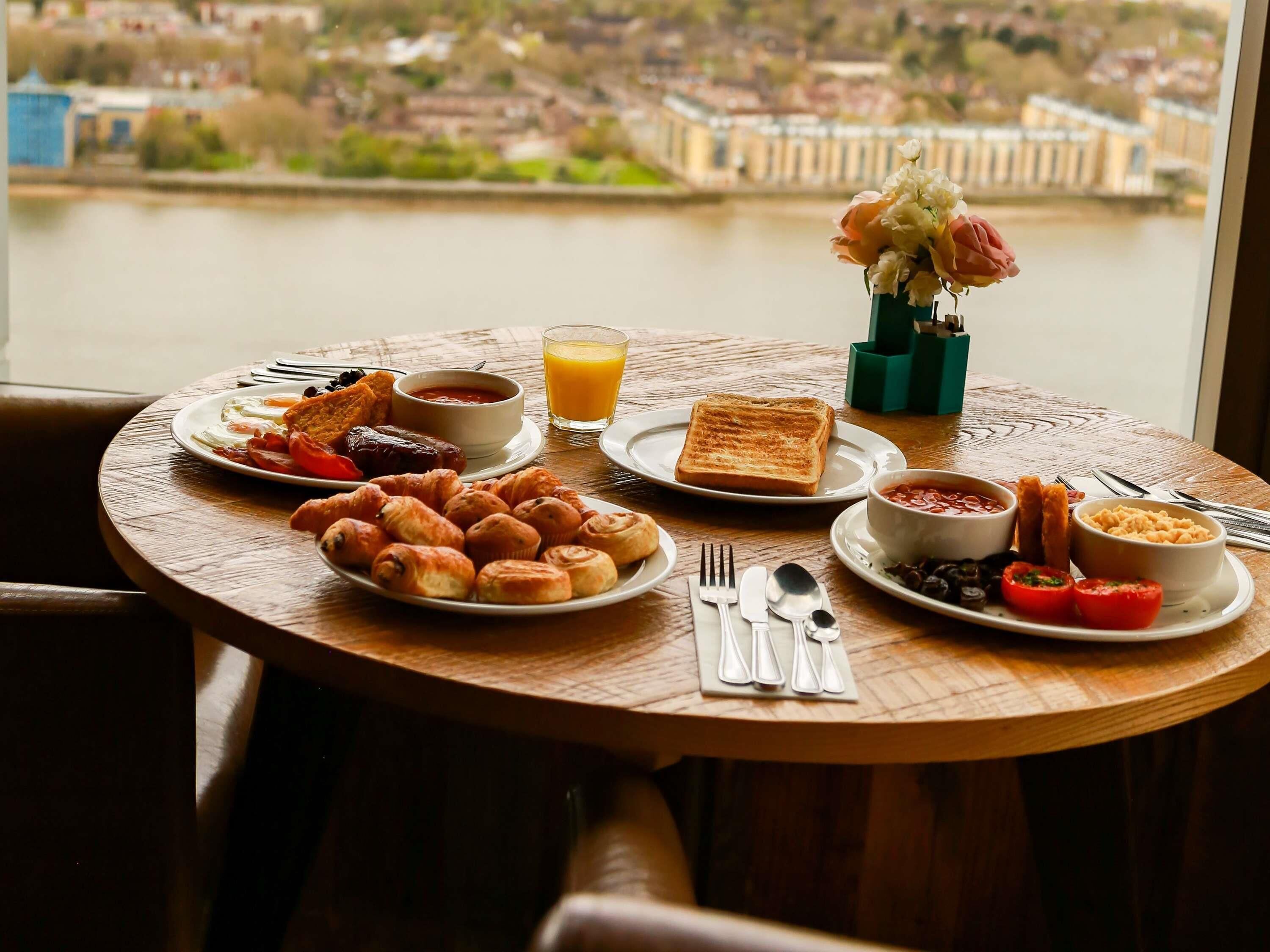 Een ontbijttafel met croissants, toast, jam en een vaas met bloemen.