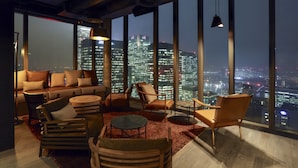 Eine moderne Lounge mit Stadtblick, ausgestattet mit einer Couch, Sesseln und einem runden Tisch.