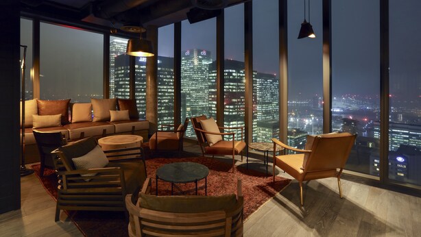 Un salon moderne avec vue sur la ville, comprenant un canapé, des fauteuils et une table ronde.