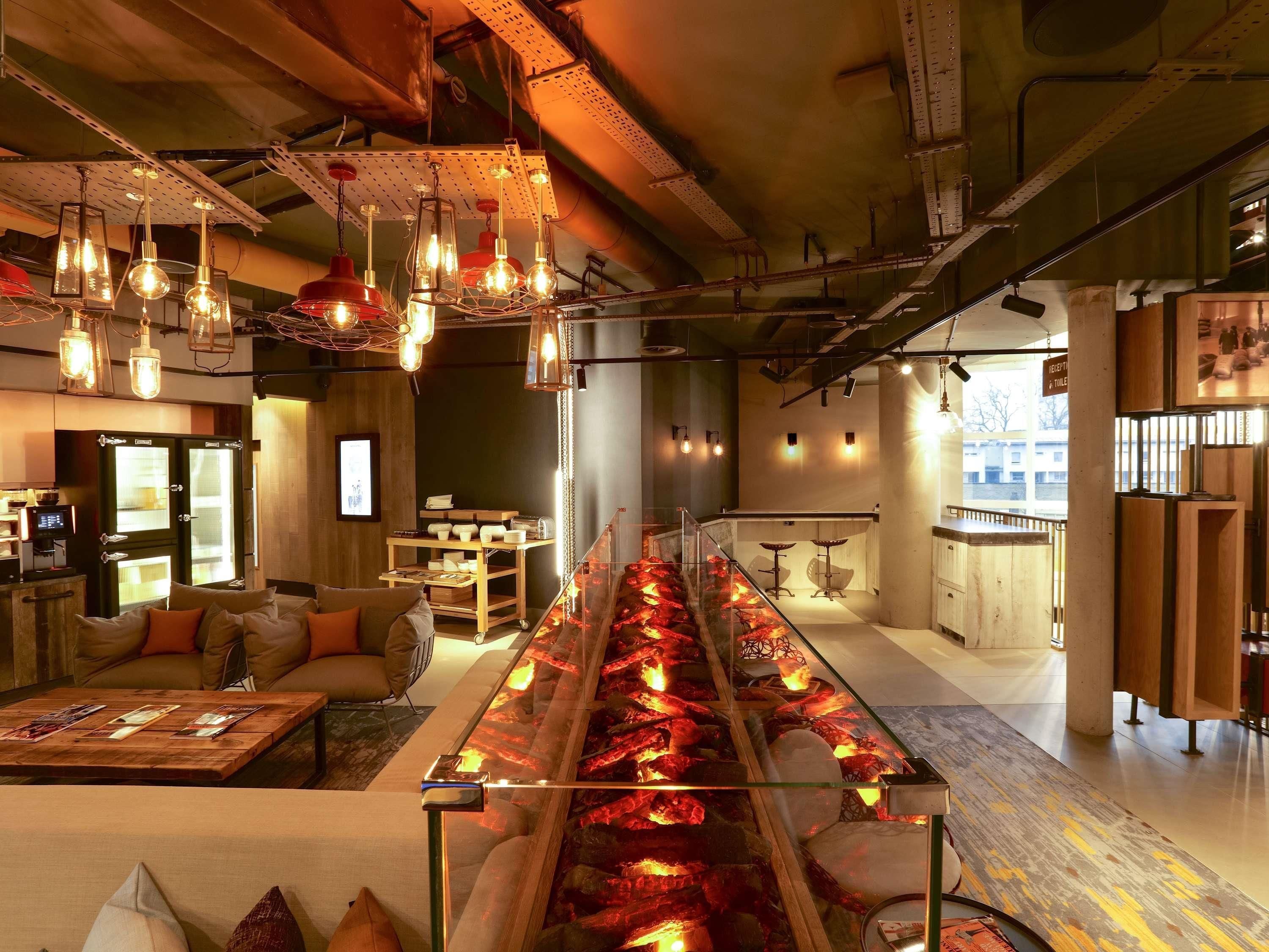 A modern interior with a long glass table featuring a heated element, seating areas with sofas, and a reception desk.