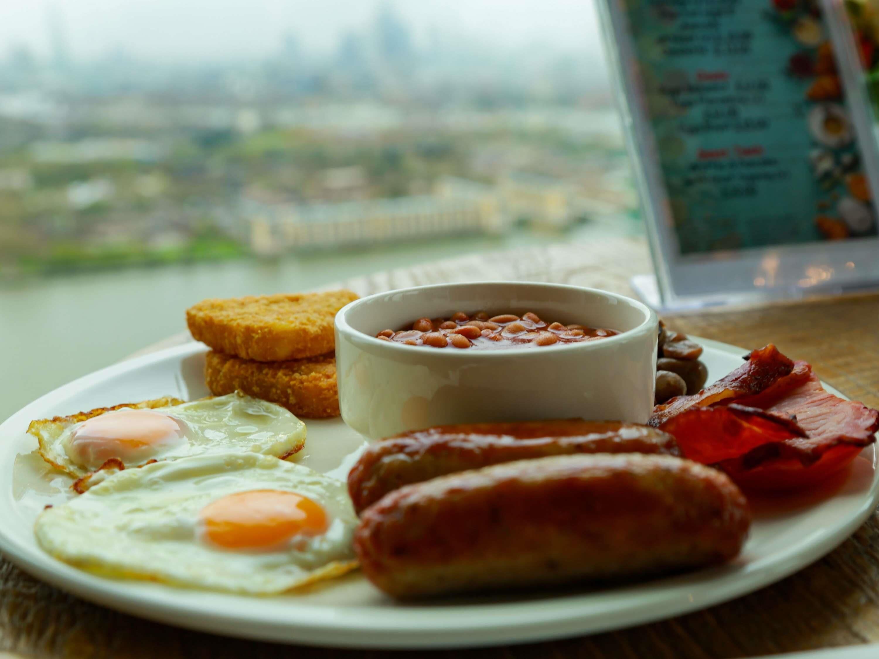 A plate of breakfast food including eggs, sausages, bacon, toast, and beans.
