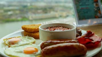 A plate of breakfast food including eggs, sausages, bacon, toast, and beans.