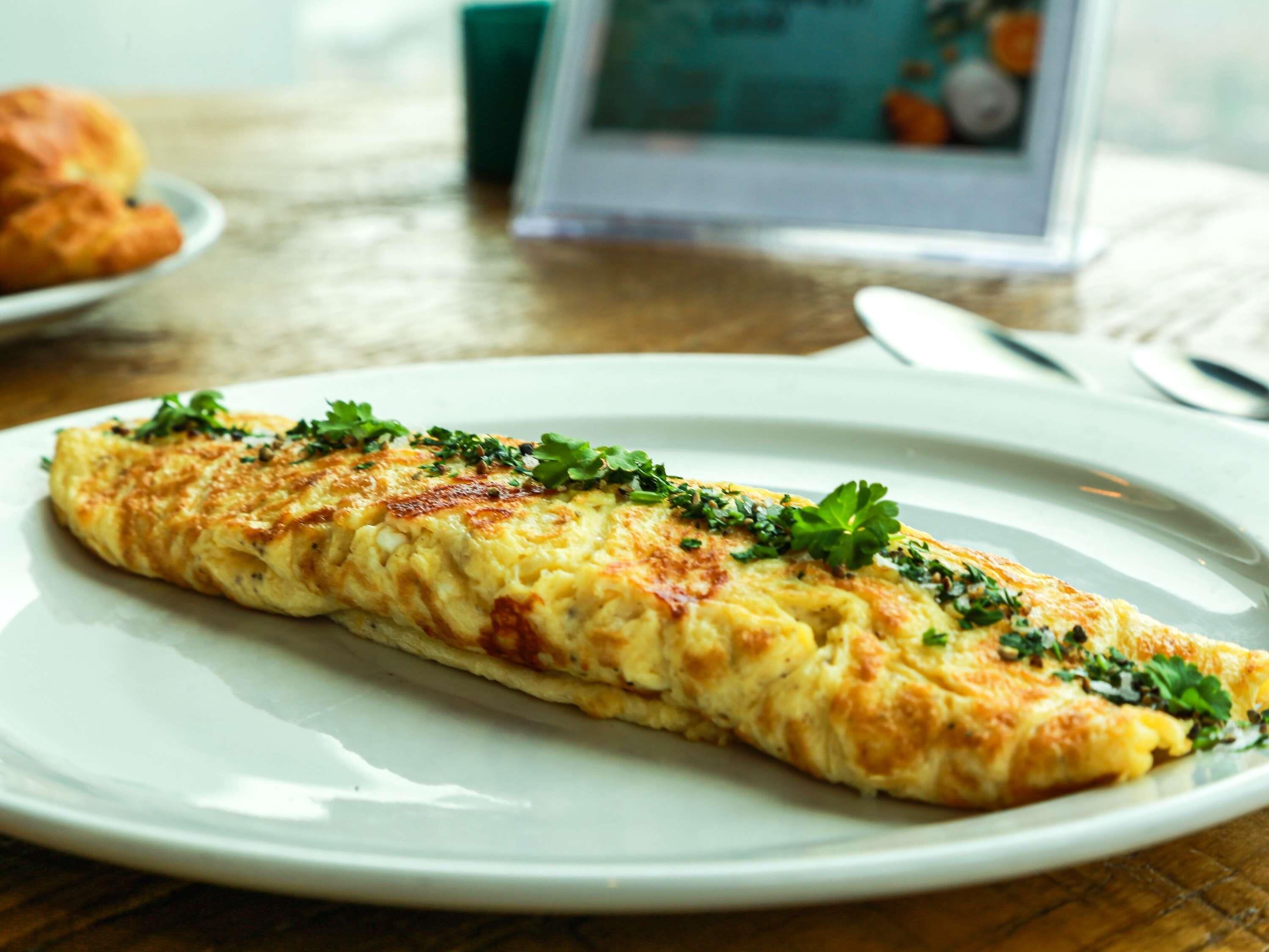 A plate with an omelette garnished with herbs.