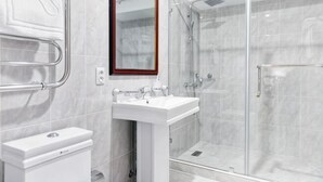 A bathroom with a white sink, mirror, and glass shower enclosure. - Shymkent Grand Hotel (Shymkent)
