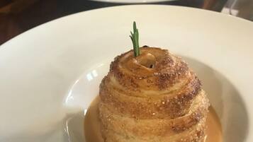 A dessert on a white plate with caramel sauce and a sprig of rosemary.