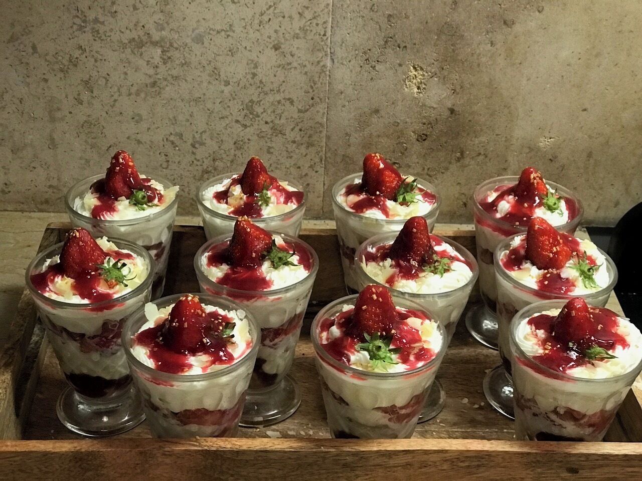 A tray of parfaits with strawberries and cream.