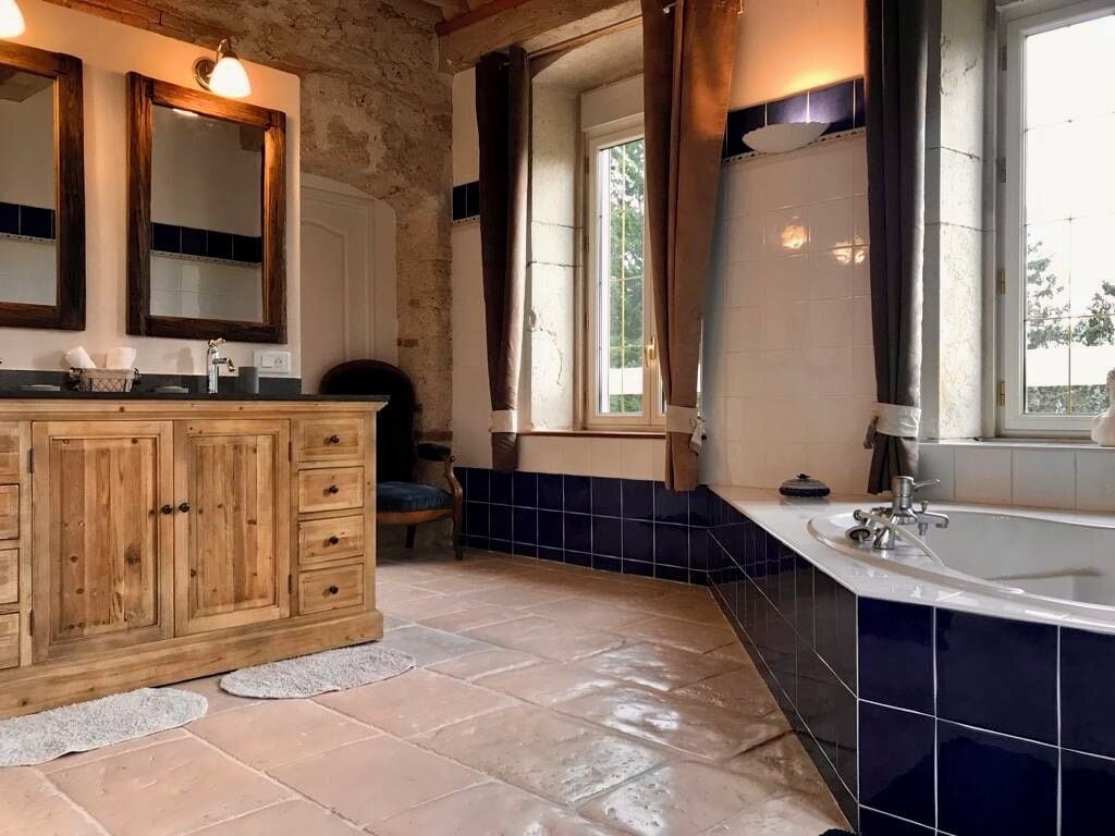 Une salle de bain avec un meuble-lavabo en bois, une baignoire et une fenêtre avec des rideaux.