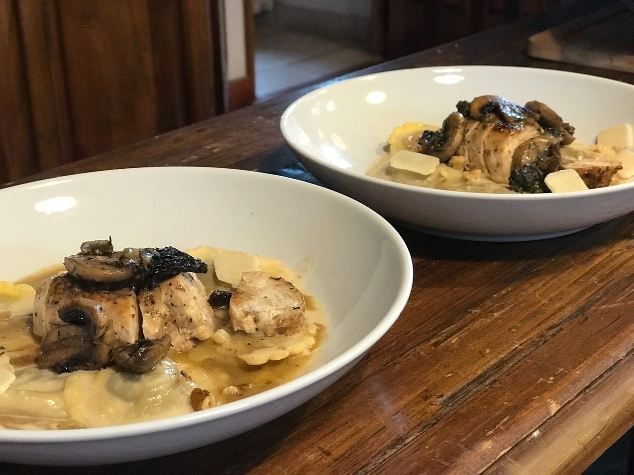 Deux bols blancs contenant un plat de poulet et de champignons, posés sur une table en bois.
