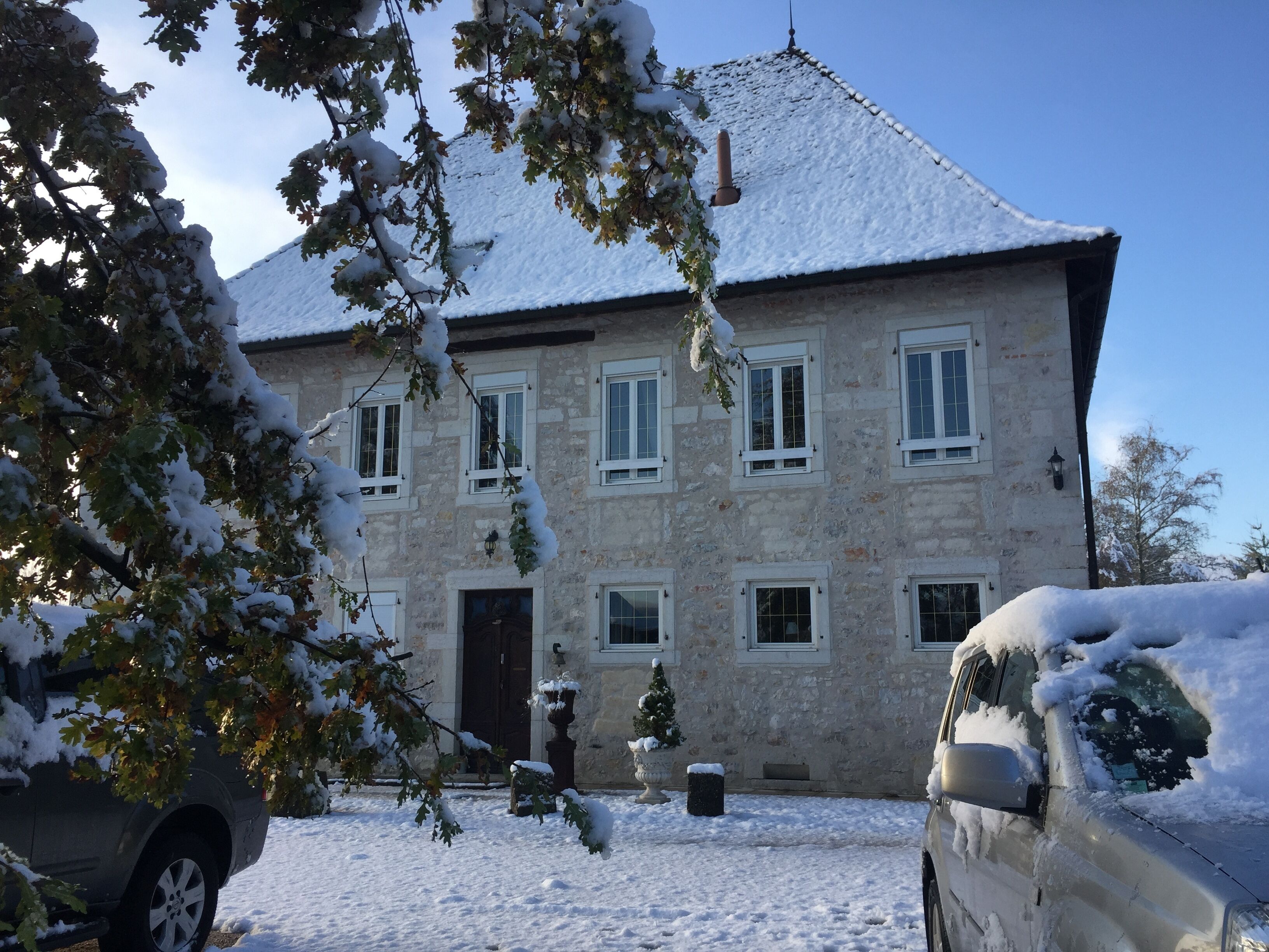 Un bâtiment en pierre doté de nombreuses fenêtres et dont le toit est recouvert de neige.