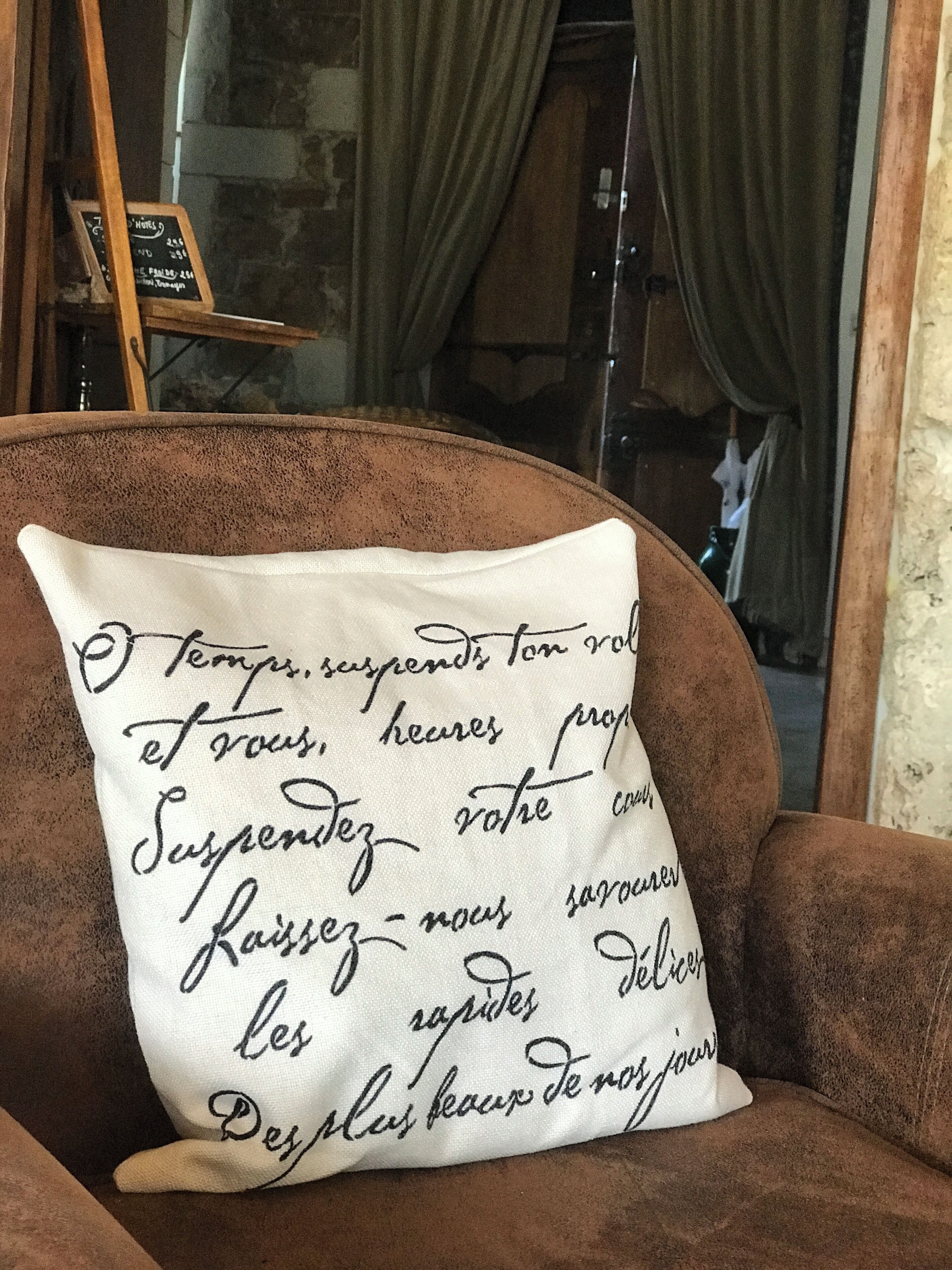 Un sillón marrón con un cojín blanco que muestra texto en francés.