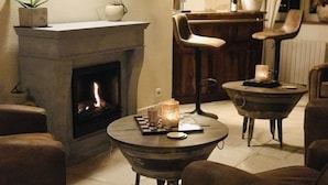 Una sala de estar acogedora con chimenea, dos mesas redondas con velas y asientos cómodos.