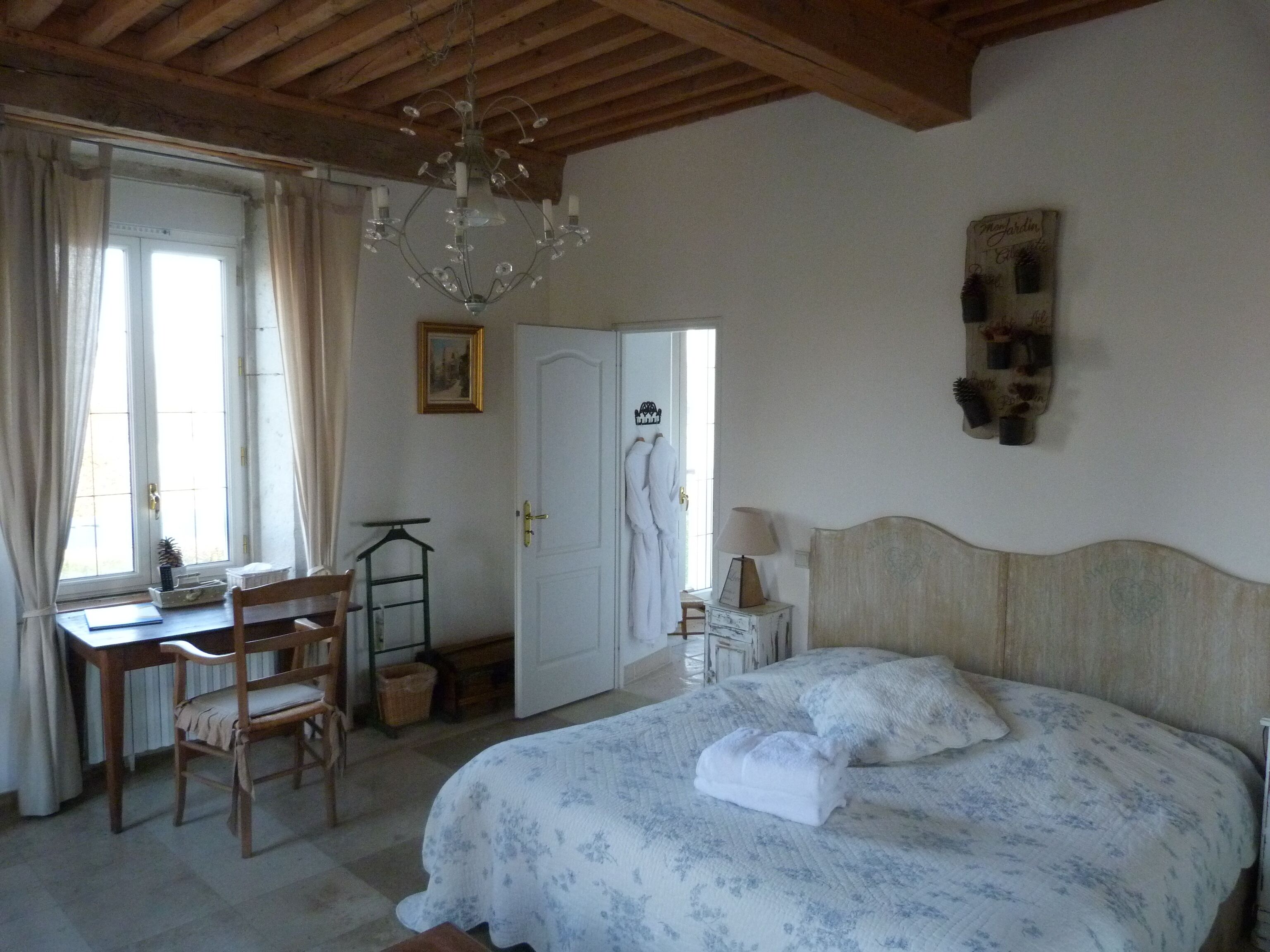 Un dormitorio con cama, escritorio, silla, candelabro y armario.
