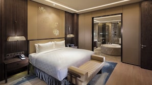 A modern hotel room with a large bed, bedside tables, a desk, and a bathroom with a bathtub and shower. - Holiday Inn Zhangjiakou Downtown by IHG (Zhangjiakou)