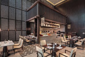 A restaurant interior with high ceilings, a central bar area, and multiple dining tables. - Holiday Inn Zhangjiakou Downtown by IHG (Zhangjiakou)