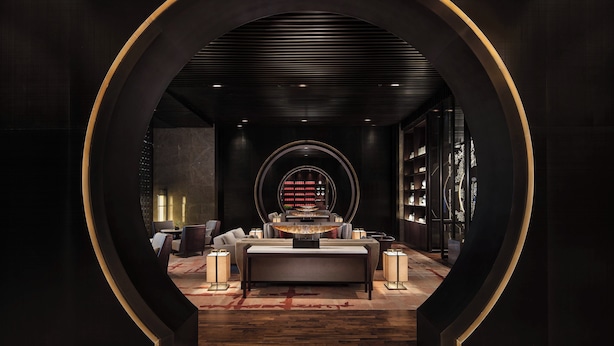 A modern, dimly lit lounge area with a central seating arrangement, a circular decorative element, and bookshelves along the walls. - Holiday Inn Zhangjiakou Downtown by IHG (Zhangjiakou)