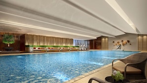 An indoor swimming pool with a seating area and a wall with vertical lines and a plant. - Holiday Inn Zhangjiakou Downtown by IHG (Zhangjiakou)