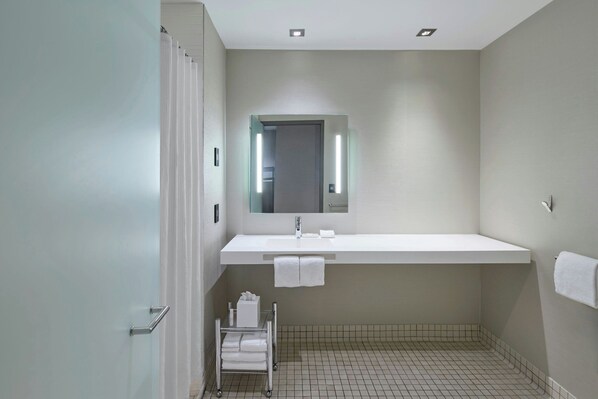 Un baño moderno con un lavamanos grande, un espejo y una zona de ducha.