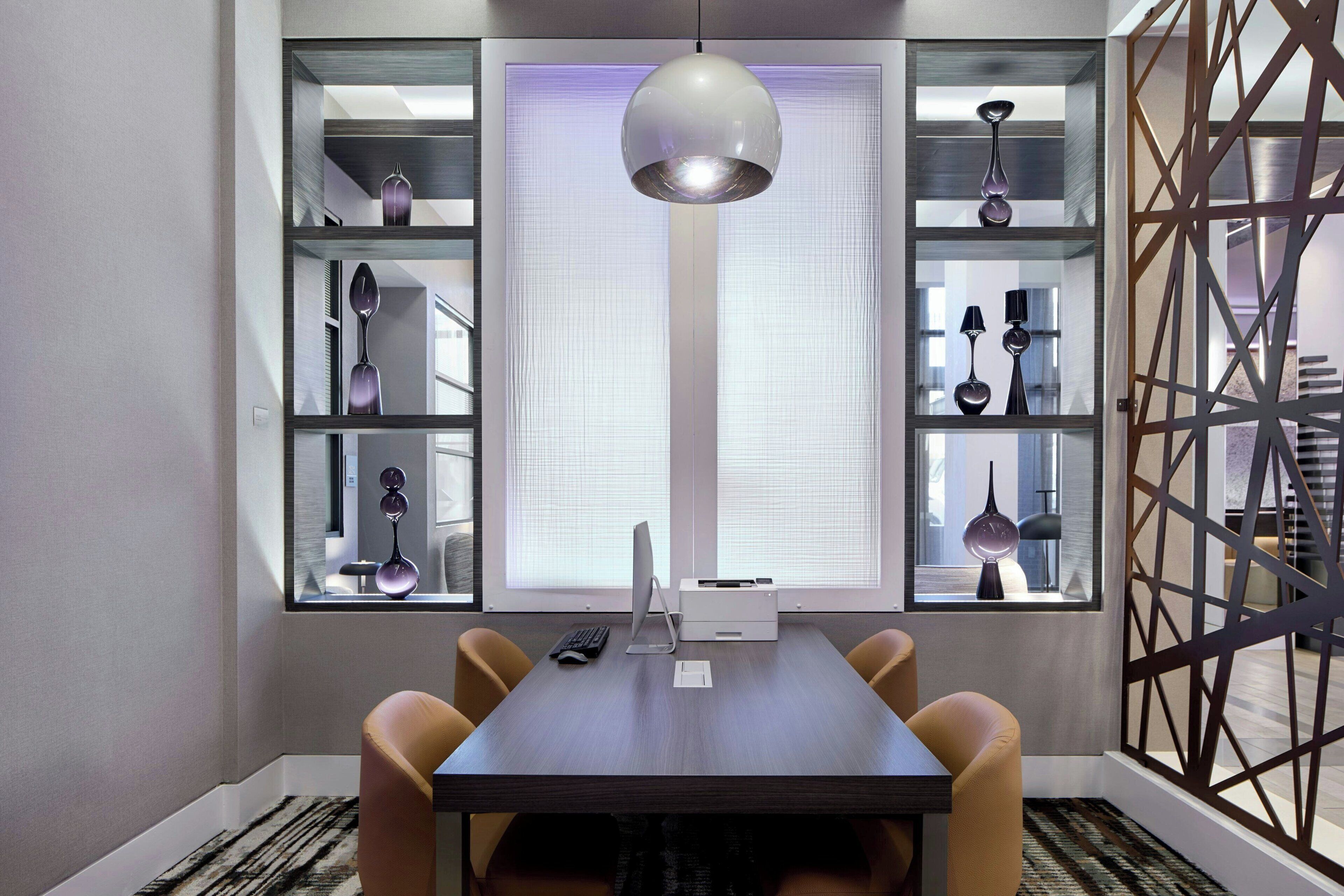 Een moderne eethoek met een donker houten tafel, twee stoelen, een hanglamp en decoratieve objecten op planken.