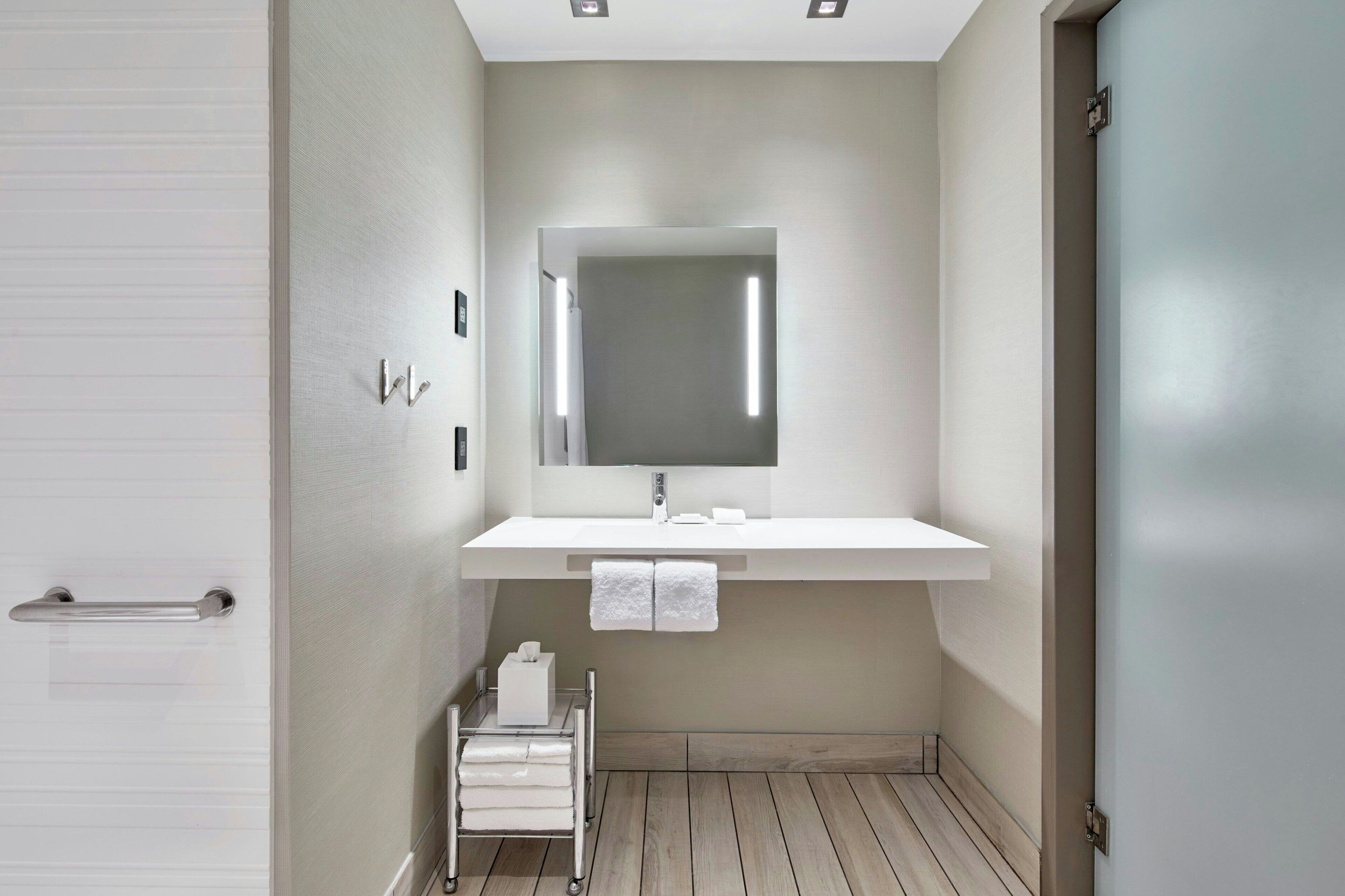 Une salle de bain moderne avec un lavabo blanc, un miroir et un petit porte-serviettes blanc.