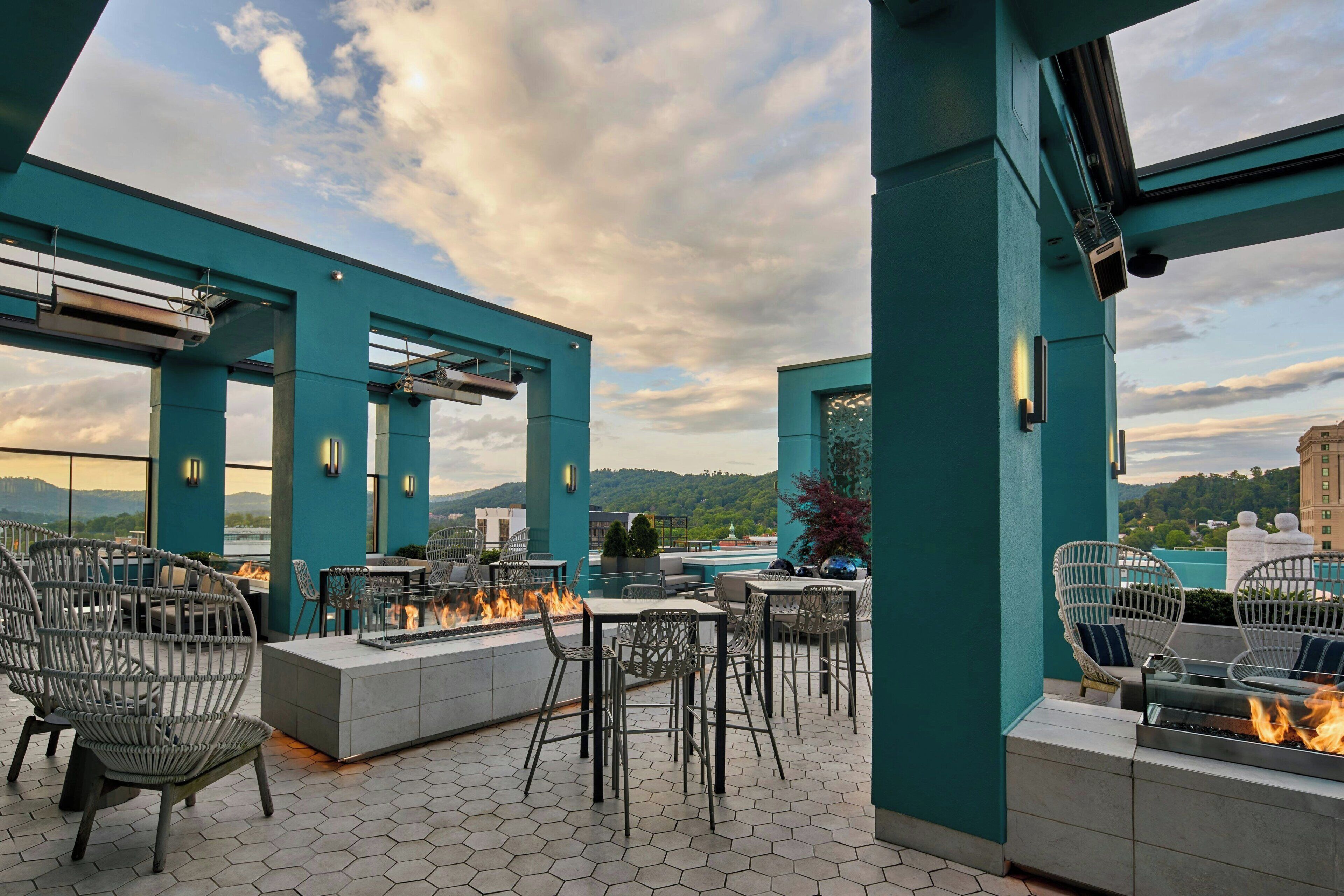 An outdoor patio with hexagonal tiles, fire pits, and wicker chairs.