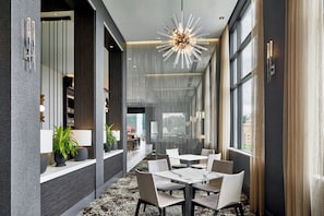 A modern interior with a dining area, large windows, and a unique ceiling light fixture. - AC Hotel Asheville Downtown (Asheville)