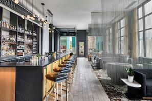 A bar area with a long counter, stools, and shelves of bottles. - AC Hotel Asheville Downtown (Asheville)