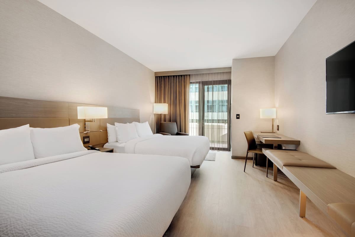 Une chambre d’hôtel avec deux lits, un bureau et une télévision.