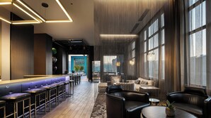 Un moderno vestíbulo de hotel con zona de bar, asientos y amplias ventanas.