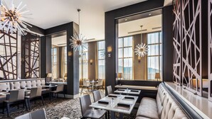 Un moderno vestíbulo de hotel con zona de estar, mesas e iluminación decorativa.
