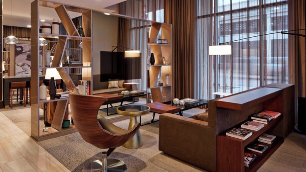 A modern living room with a sofa, coffee table, and a wooden bookshelf.