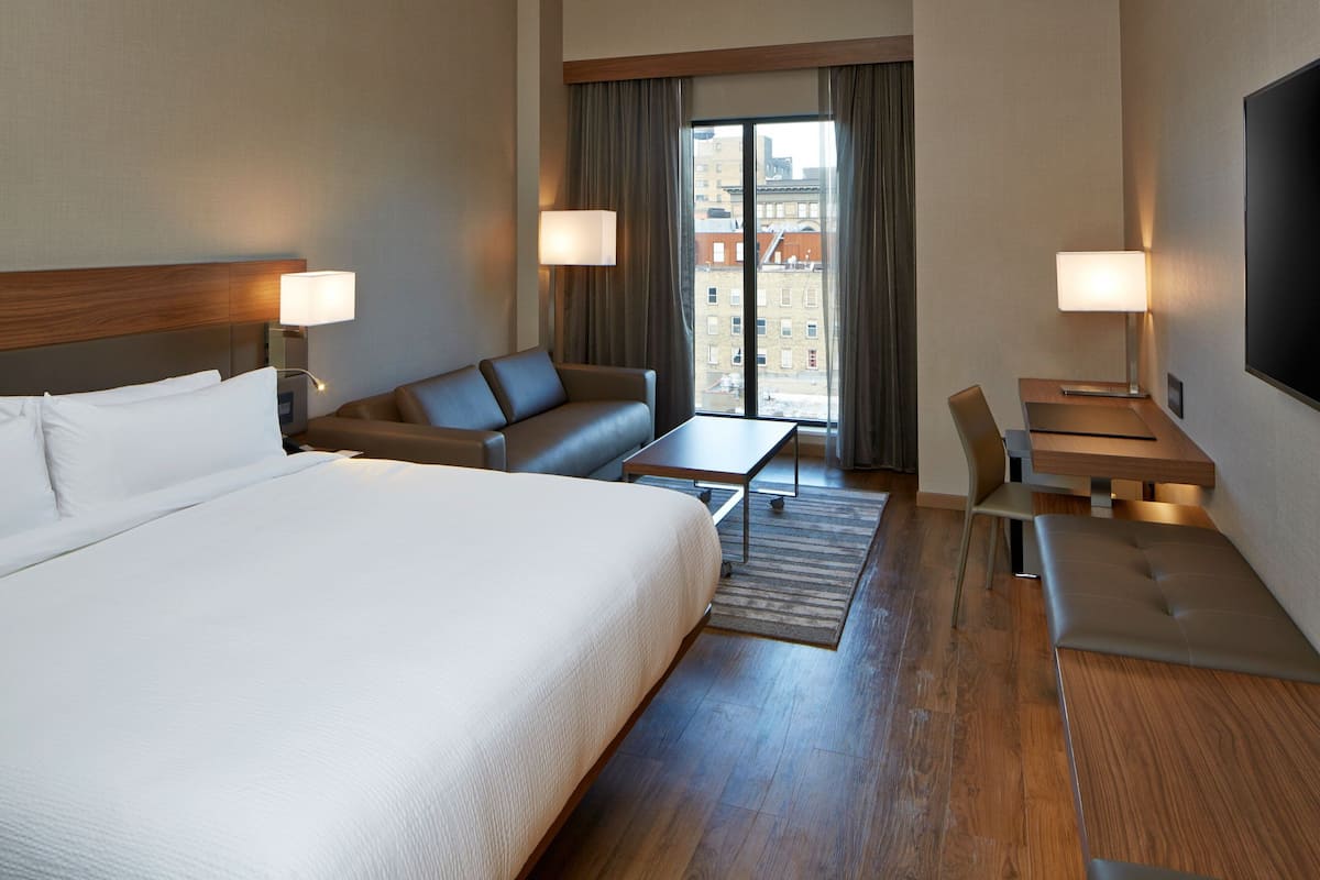 Una habitación de hotel con una cama grande, un sofá, un escritorio y una televisión.
