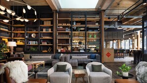 Un interior moderno con un sofá, sillones, una mesita de café y una estantería.