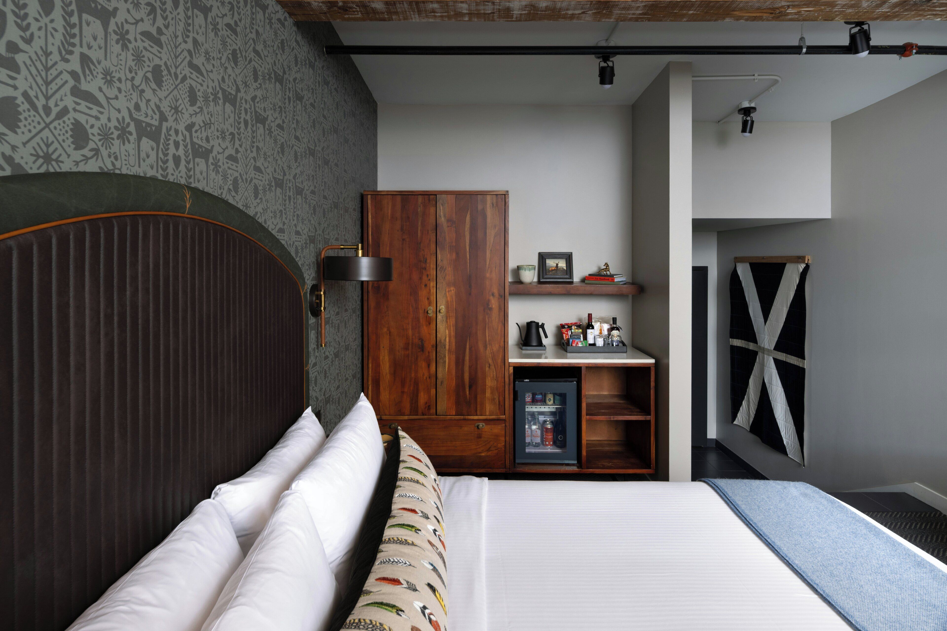 A bedroom with a bed, a wardrobe, a shelf with items, and a window with a cross-braced design.
