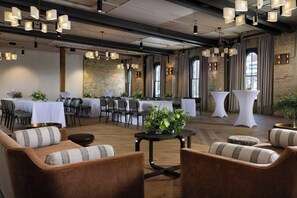 A spacious room with a long table set for dining, multiple seating areas, and large windows.