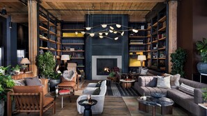Una sala de estar acogedora con chimenea, estanterías, muebles de cuero e iluminación colgante.