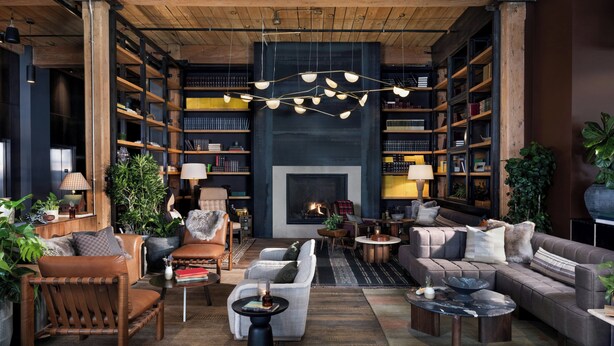 A cozy living room with a fireplace, bookshelves, leather furniture, and hanging lights. - Hewing Hotel (Minneapolis)