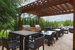 Um pátio externo com pérgola, espaço para churrasco e área de estar.