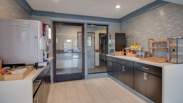 A modern kitchen with a refrigerator, cabinets, and a countertop with various items. - Americas Best Value Inn Hayward (Hayward)