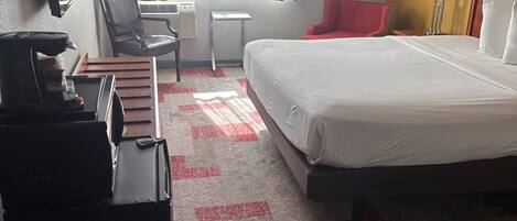 A hotel room with a bed, a desk, a chair, a TV, and a coffee machine.