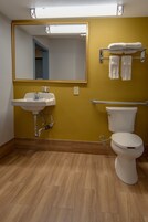 Un baño con lavamanos, espejo, inodoro y toallero.