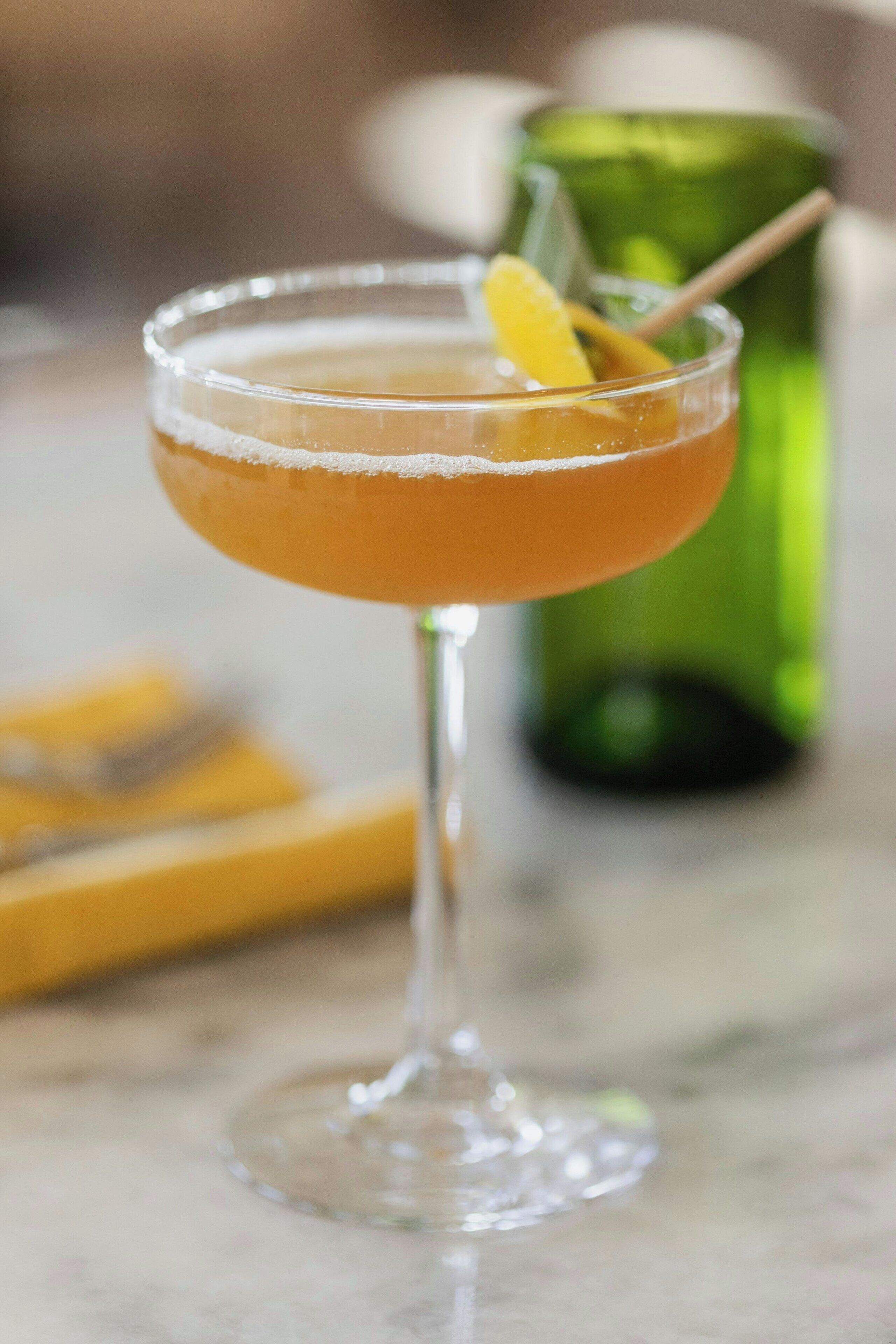A cocktail in a stemmed glass with a lemon garnish.