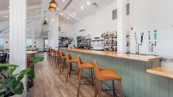 A bar area with wooden stools, a counter, and shelves stocked with bottles.