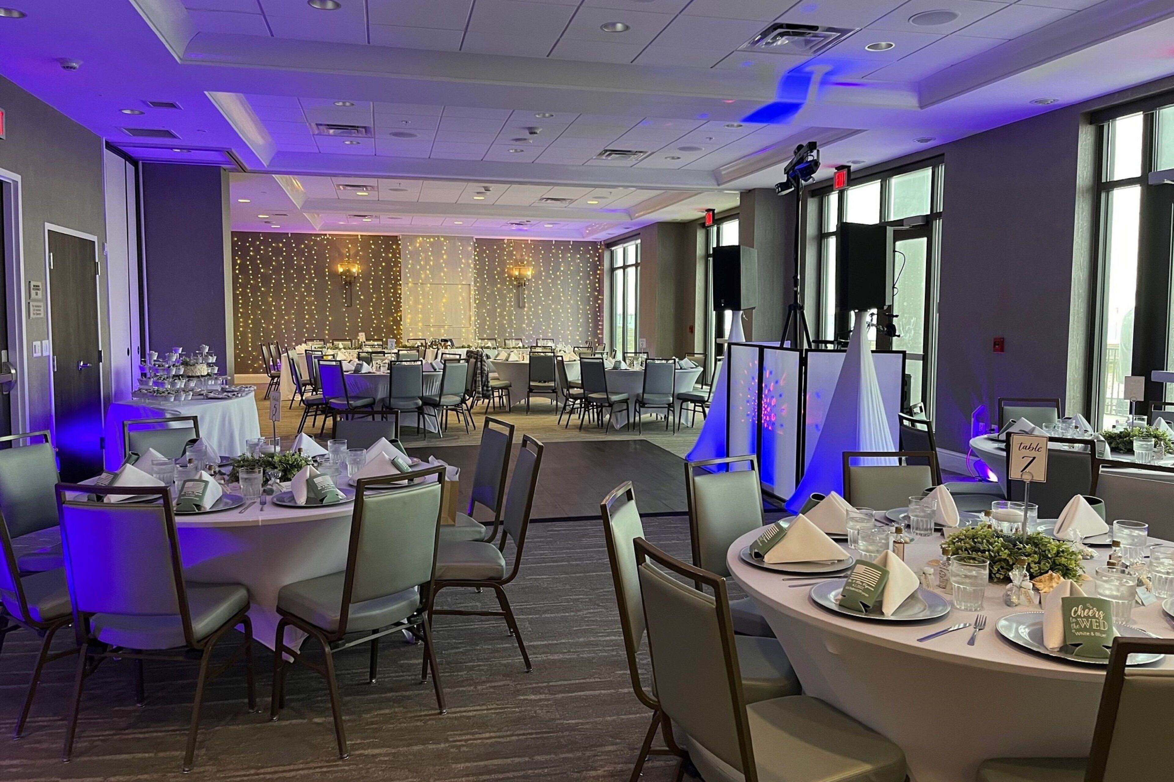 A banquet hall with round tables set for a formal event, equipped with name cards and table settings.