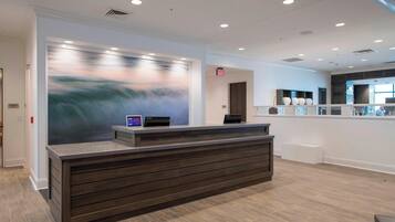 A modern reception desk with a digital display, a large abstract painting, and a clean, minimalist design.
