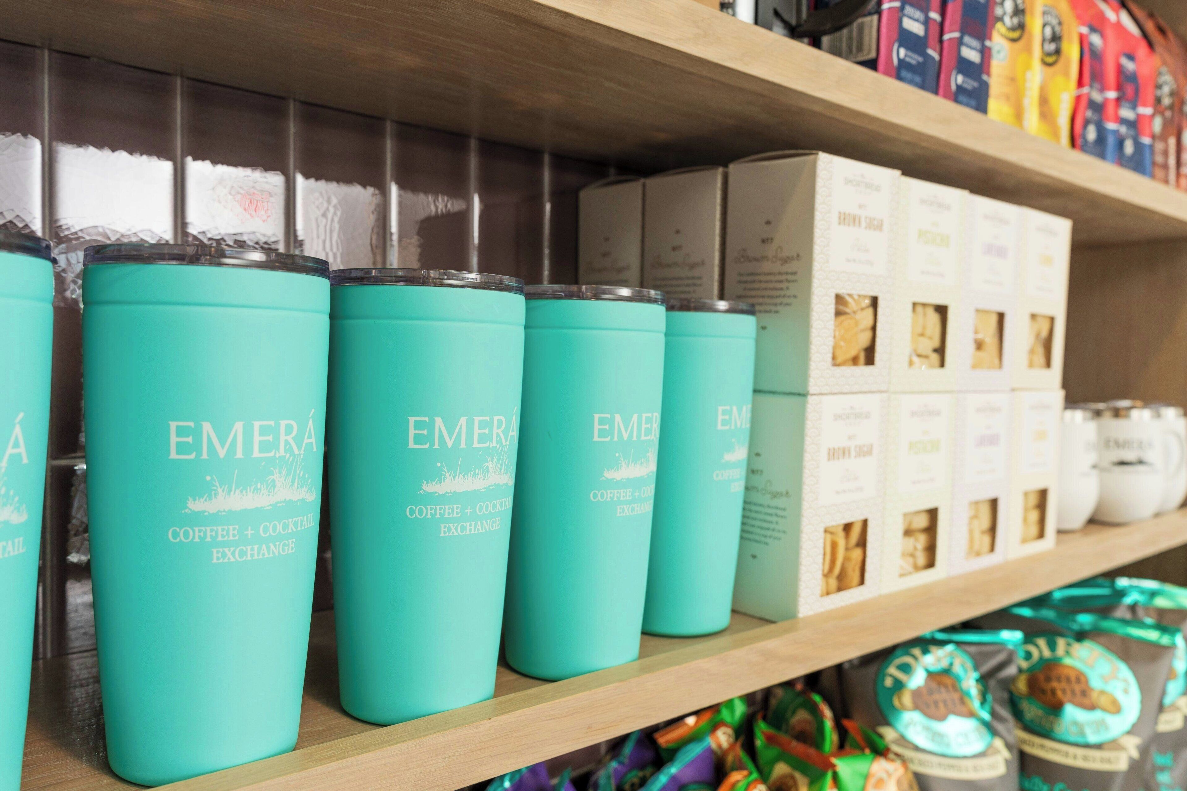 Een plank met kisten in blauwgroene tint en diverse koffieproducten, gelabeld 'EMERA'.