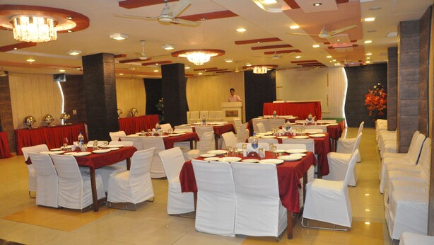 A banquet hall with round tables set for dining, white chairs, and red tablecloths.