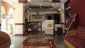 A lobby with a reception desk, a chandelier, a clock, and a sofa.