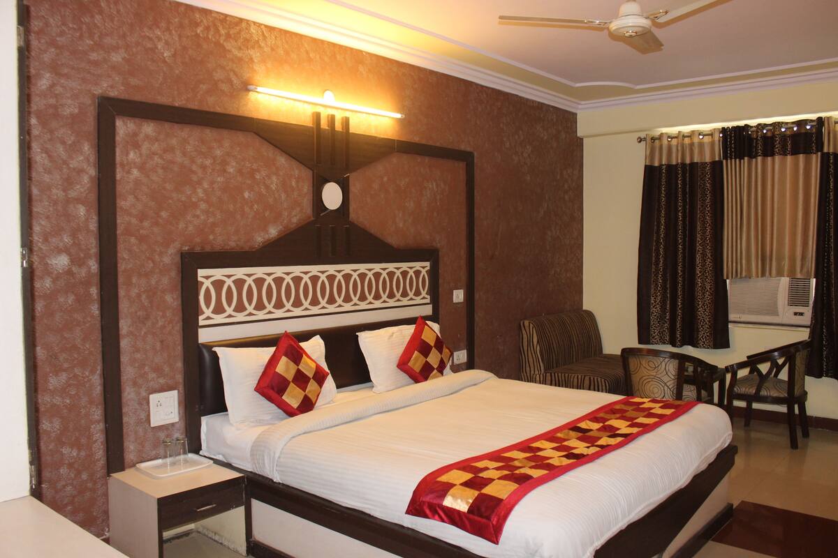A hotel room with a large bed, a desk, and a chair.